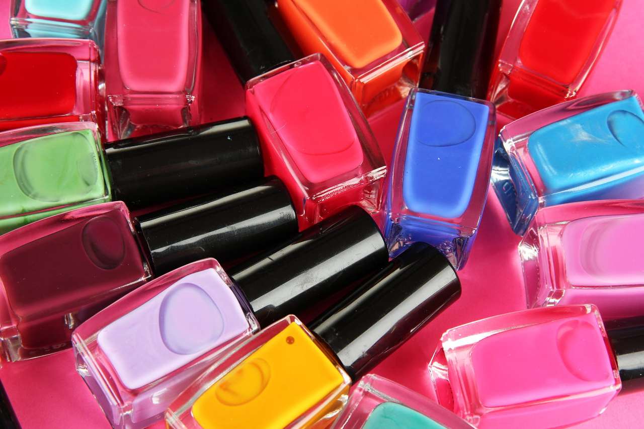 Esmalte de uñas de color sobre un fondo rosa rompecabezas en línea