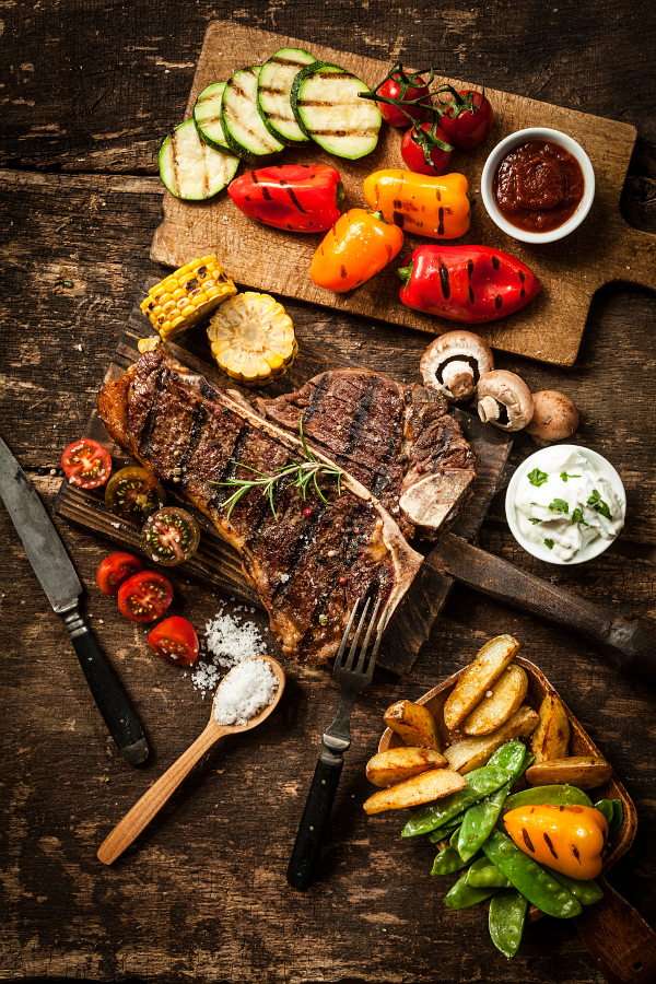 Grilled T-bone steak with sides on a wooden table online puzzle
