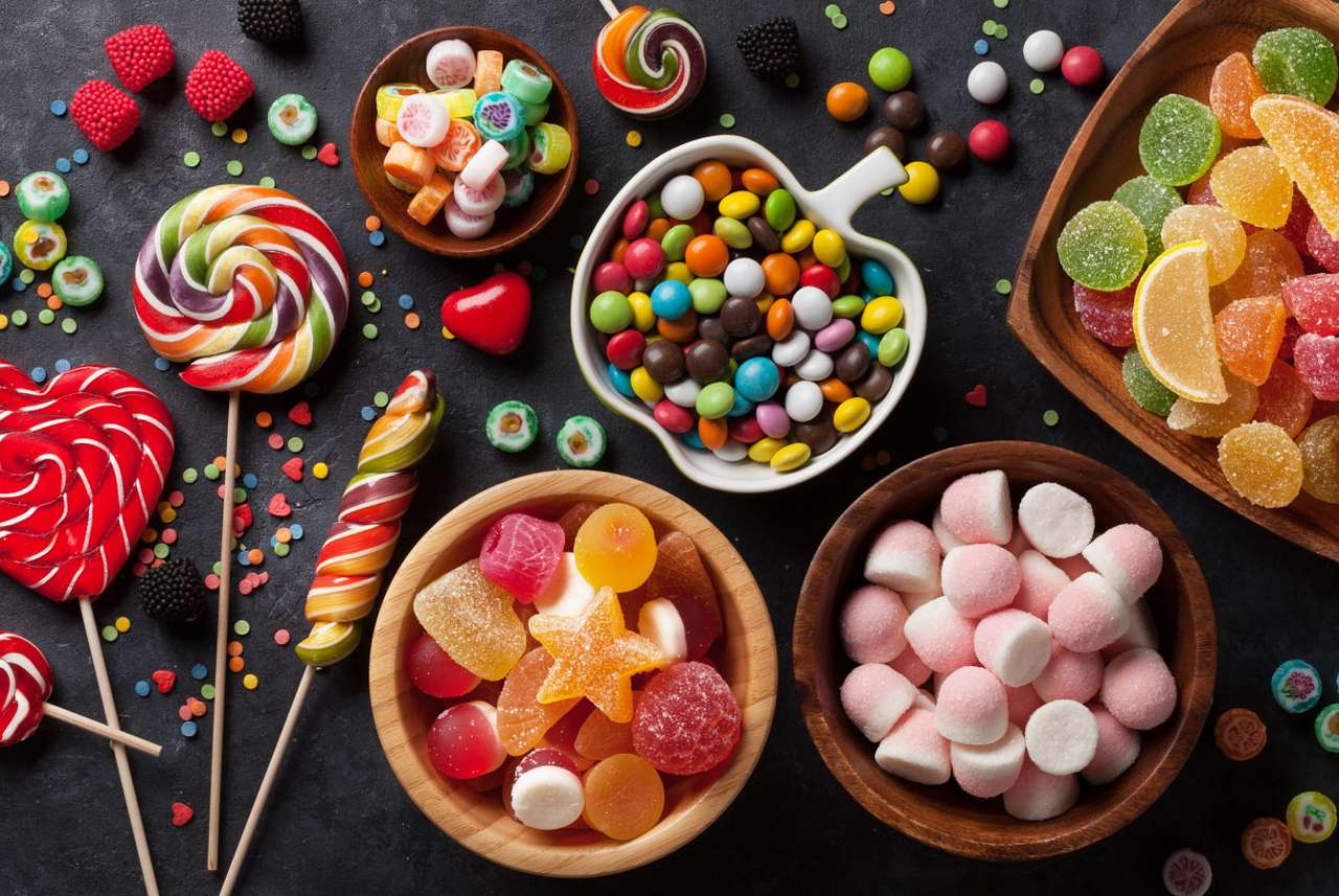 Caramelos de colores, piruletas y gelatina sobre una encimera oscura rompecabezas en línea