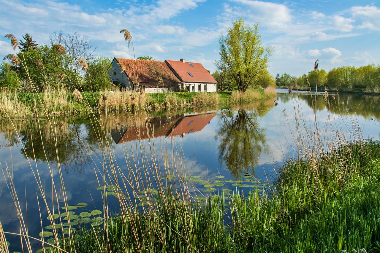 Maison au dessus de la rivière, arbres et ciel bleu. Beau paysage de printemps en Pologne puzzle en ligne à partir d'une photo